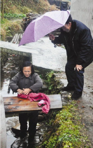 庆元合湖村，73岁的刘祖良佝偻着腰，给65岁的刘香花撑着伞。范正民 摄