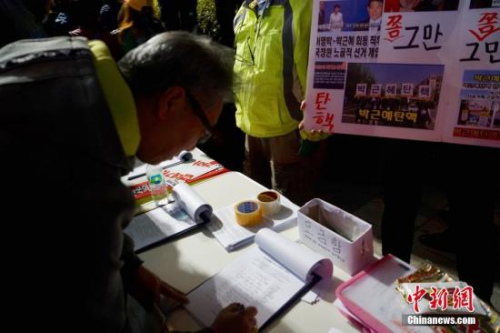 10月29日晚，近两万名韩国民众及民间团体人士在首尔市中心举行烛光集会，谴责“亲信干政事件”给韩国社会带来的不良影响，要求总统朴槿惠对此事负责。图为民众在集会现场写下请愿书，要求查明事情真相。<a target='_blank' href='http://www.chinanews.com/'><p align=