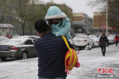 11月21日，北京降下今冬初雪，路面湿滑，一位家长扛着孩子外出。<a target='_blank' href='http://www.chinanews.com/'>中新社</a>记者 杨可佳 摄