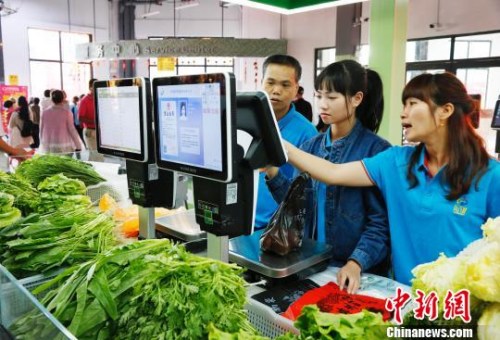 资料图：1月16日，三亚乐天城农贸市场内，摊主在操作智能系统。　尹海明 摄