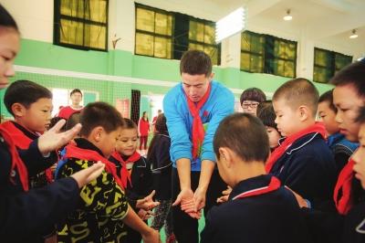 沙排冠军变 孩子王 李健教他们打排球手势(图)