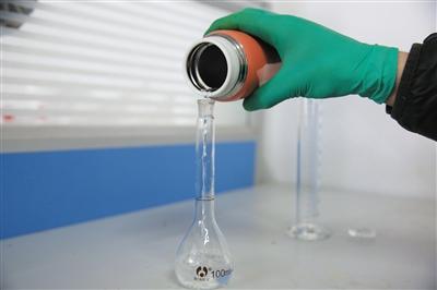 实验人员将保温杯内配比好的醋酸溶液倒入定量瓶。
