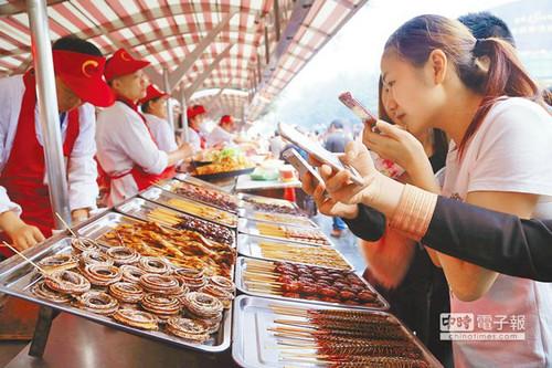 北京一“蟲子宴”攤位，擺滿串蛇、蜈蚣、螞蚱、蜘蛛等，不少食客拿出手機拍照。(臺灣中時電子報)
