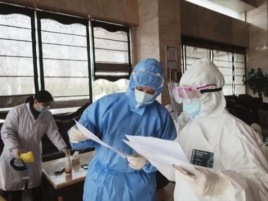3月7日，硚口区汉水桥街道社区卫生服务中心医生黄莹(右二)在解放大道隔离点核对患者信息。
