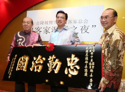 吴德芳（左）赠送“忠勤治国”牌匾给廖中莱，祝贺他受委出任交通部长。右为林济升。