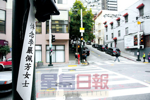 中国侨网路口的两个电灯柱上，还绑着丝绸花束和黑丝带悼念车祸身亡的华裔妇女。（美国《星岛日报》/黄伟江 摄）