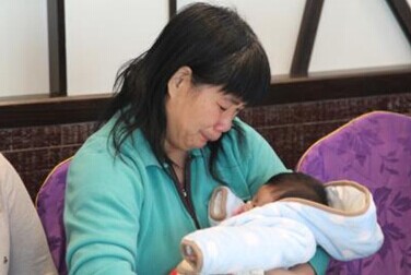 中国侨网马日凤的母亲看着怀中遗婴，不住落泪。(美国《世界日报》/洪群超 摄)