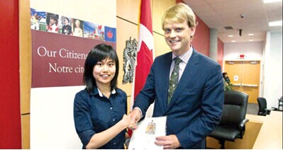 中国侨网加拿大移民部长亚历山大（右）早前出席公民入仪议式，颁发公民证书给华裔。（加拿大《明报》）