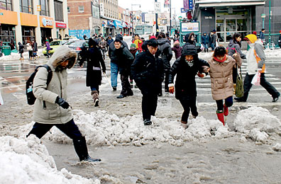 中国侨网法拉盛商业中心区罗斯福大道夹缅街，积雪溶化成雪泞。游人一不小心就会踩进又冷又湿滑污水，狼狈和滋味不好受。（美国《星岛日报》）