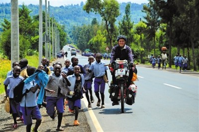 在乌干达，放学的孩子们追着杜风彦的自行车一起跑。