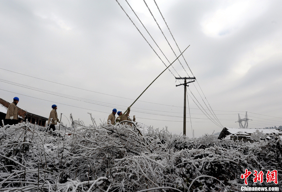 贵州遭凝冻天气 工人用竹竿清除电线积冰