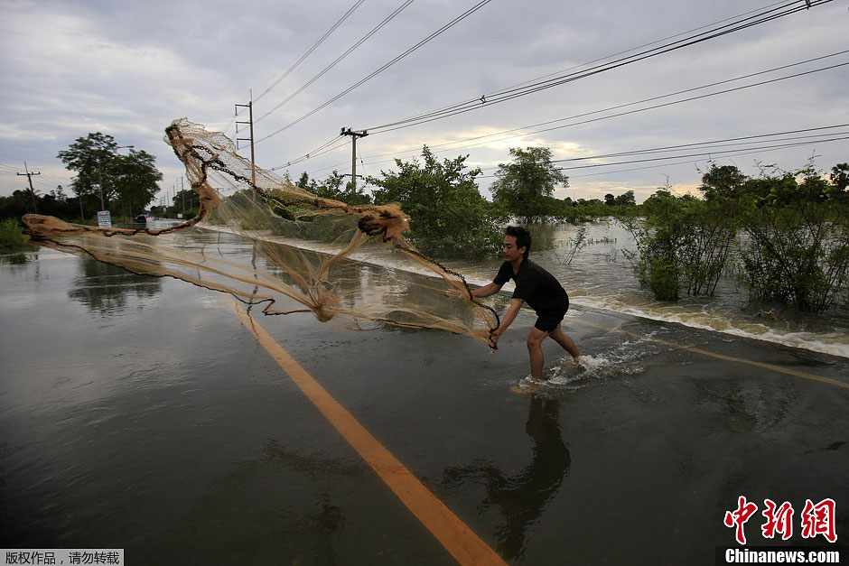 泰国遭受洪水侵袭 民众街头撒网捕鱼