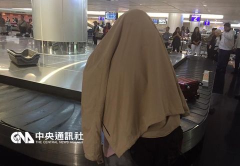 在华航班机上产女的台湾女子已返台，她下飞机后，用夹克盖住自己的身体。（台湾“中央社”）