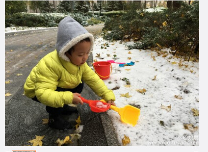 Yao son take a small shovel to play with snow doll in the snow 