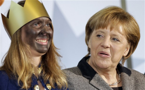 德国总理默克尔与一名涂黑脸女孩合影,撅嘴扬眉露古怪神情( 德国总理默克尔与一名涂黑脸女孩合影,撅嘴扬眉露古怪神情(