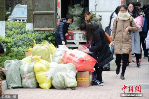 2月21日，山东青岛，不少高校已经开学，新学期开始，位于山东青岛一高校校园内各大快递点业务量陡增，不少学生开学前后网购的物品陆续到达学校，快递点前取快递的同学排起长龙，快递堆成一个个小山，一个快递点排队的长龙甚至横跨了整条公路，场面壮观。skd 摄 图片来源：视觉中国