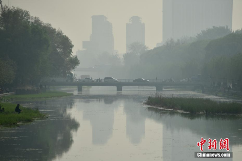 北京迎来沙尘天气市区能见度降低，市民佩戴口罩出行。 中新网记者 金硕 摄