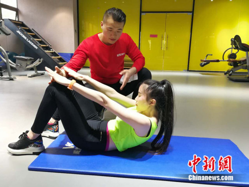 健身教练在健身房指导学员 中新网记者 张尼摄