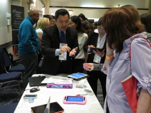 林欣(左)为参观者讲解公司设计的App。(美国《世界日报》/陈小宁 摄) 林欣(左)为参观者讲解公司设计的App。(美国《世界日报》/陈小宁 摄)