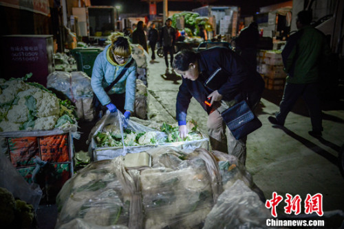 凌晨正在批发蔬菜的老丁。中新网记者 富宇 摄 凌晨正在批发蔬菜的老丁。中新网记者 富宇 摄