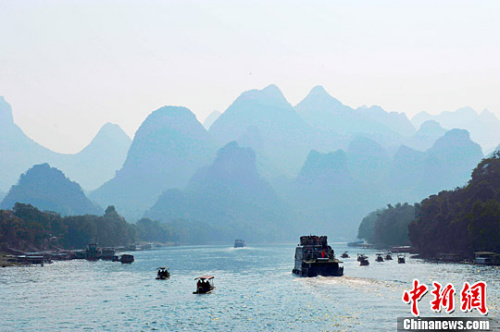 资料图：游人乘坐游船行驶在桂林漓江上面游玩观赏美丽的漓江风光，呈现烟雨漓江的画卷。胡雁 摄