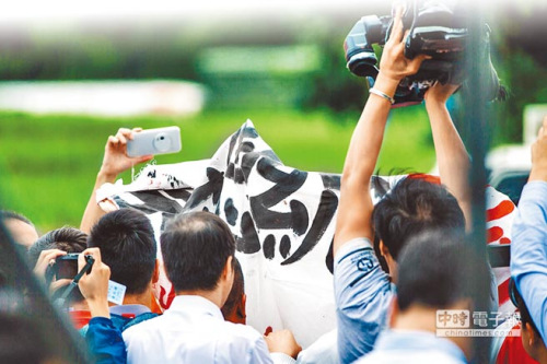 蔡英文28日出席台北国际龙舟锦标赛，却遇到高速公路收费员自救会在后台高举布条标语抗议，但随即遭现场警力驱离。（图片来源：台湾《中时电子报》）