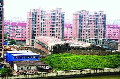 倒塌的楼房位于河边,底部折断的水泥柱裸露在外。