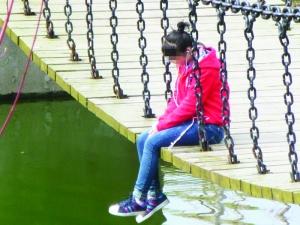年轻女孩坐吊桥边听歌 身体跟着音乐晃吓坏路人