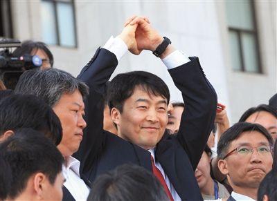 4日,被逮捕后的李石基向媒体微笑示意。