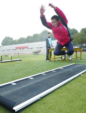 一名男生在立定跳远模拟测试的垫子上起跳.