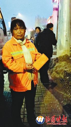 环卫工张素萍拿着失主的空钱包src=