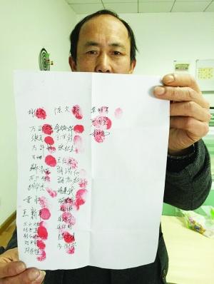 胡先生向记者展示工友签名盖手印的白纸