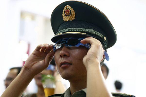 资料图:一名军人戴上参展商准备的眼镜观看3d成像的大屏幕.