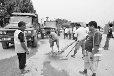 郑州新修马路被沙土覆盖 60多名环卫工怒堵沙石车