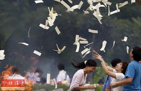 2012年4月4日清明节,在新加坡的一个华人公墓,人们向空中抛撒纸钱