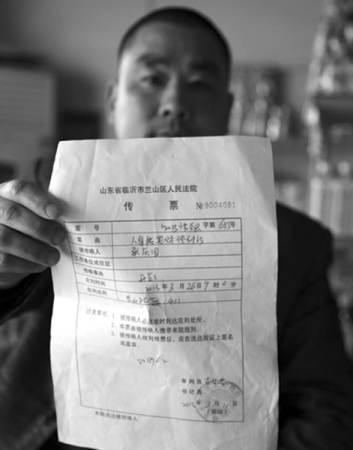 张庆国向记者展示法院传票