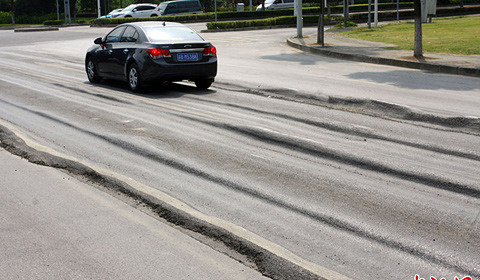 路口,在连日高温与大吨位工程车的双重压力下,两车道柏油路面严重凹陷