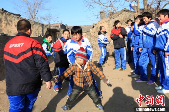 图为"面具娃娃"湘湘与学生们做老鹰抓小鸡的游戏.中新社发 韦亮 摄