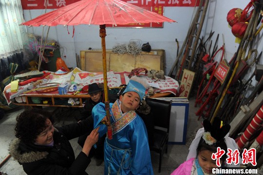 59岁的雷明珍正忙碌着给小演员穿戴戏服.张浪 摄