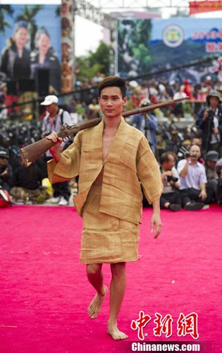 图为一位肩扛猎枪的黎族展示他身上用"见血封喉"树皮制成的树皮衣