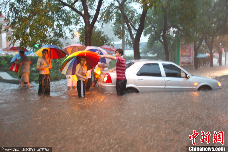 北京暴雨 情侣雨中搀扶前行-中新网