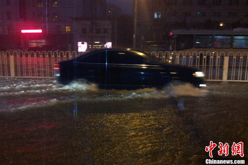 北京暴雨 情侣雨中搀扶前行-中新网