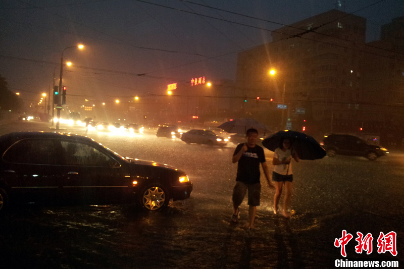 北京暴雨 情侣雨中搀扶前行-中新网