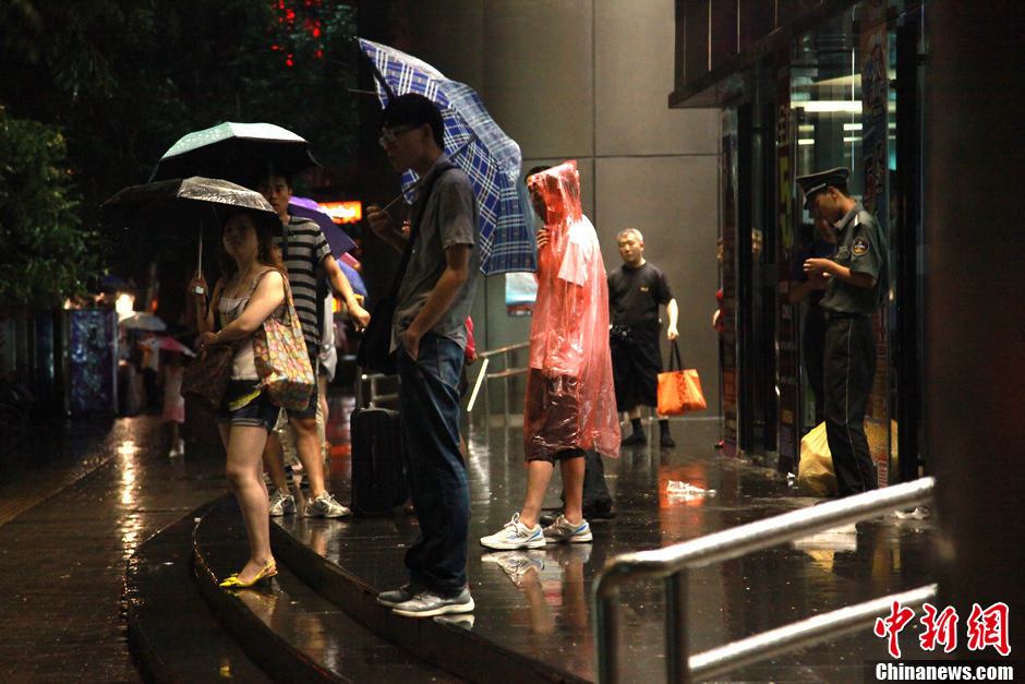 北京暴雨 情侣雨中搀扶前行-中新网