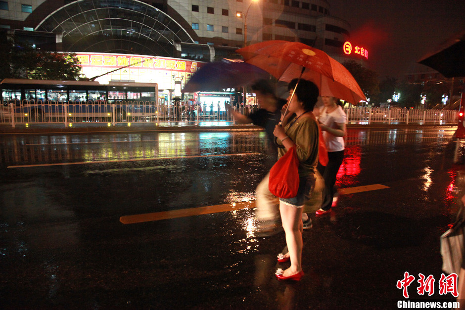 北京暴雨 情侣雨中搀扶前行-中新网