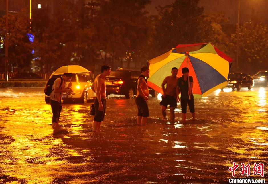 北京暴雨 情侣雨中搀扶前行-中新网