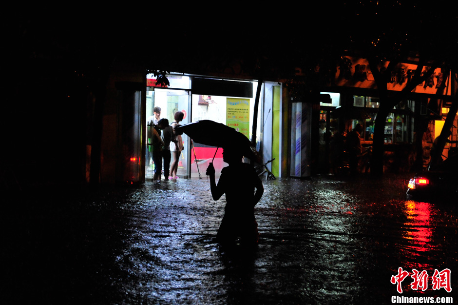 北京暴雨 情侣雨中搀扶前行-中新网
