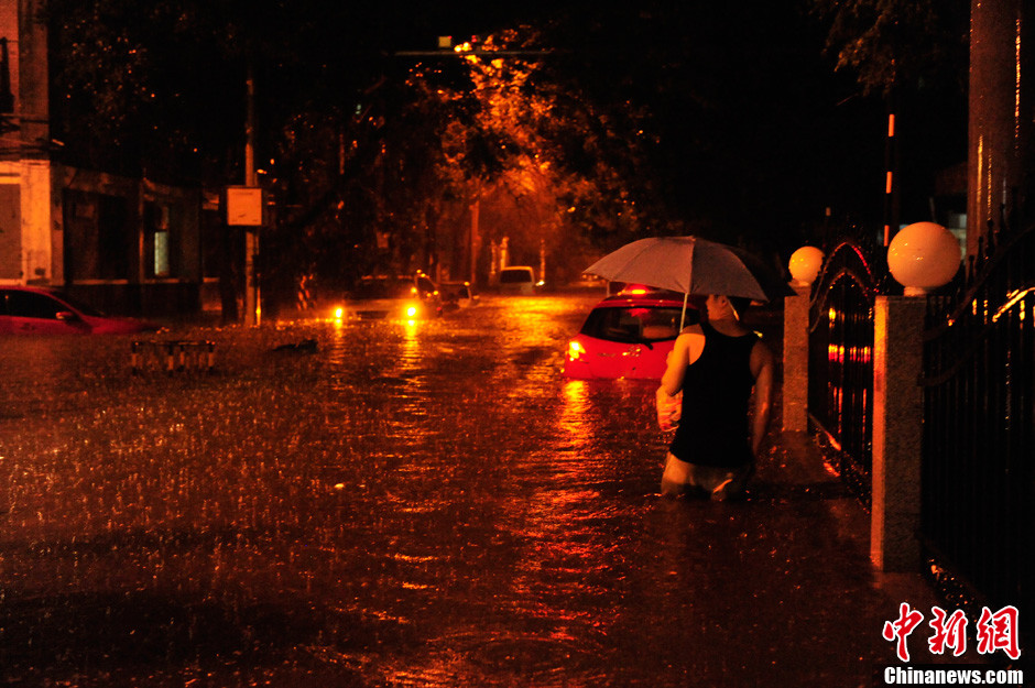 北京暴雨 情侣雨中搀扶前行-中新网