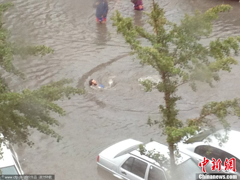 北京暴雨 情侣雨中搀扶前行-中新网
