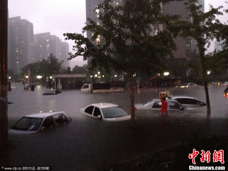 北京暴雨 情侣雨中搀扶前行-中新网